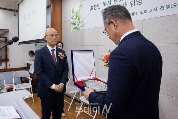 서전주노회장이 정재식 목사에게 위임패를 전달하며 교회의 공식적인 새 출발을 축복하고 있다.